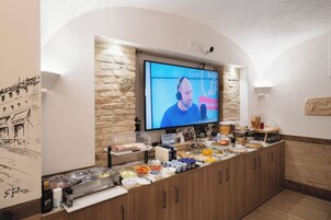 A breakfast bar with a variety of food items and a television screen displaying a person speaking.
