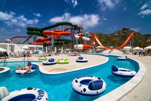 A swimming pool with multiple water slides and inflatable rings.