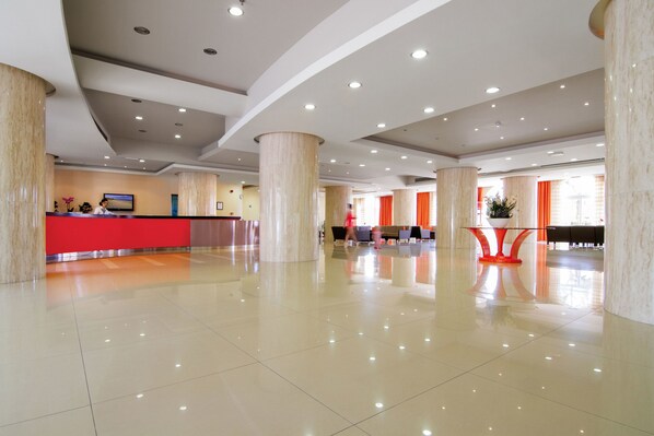 A spacious lobby with a reception desk, large pillars, and a polished floor.