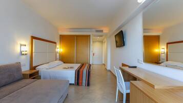 Ein Hotelzimmer mit zwei Betten, einem Sofa, einem Schreibtisch und einem Fernseher.