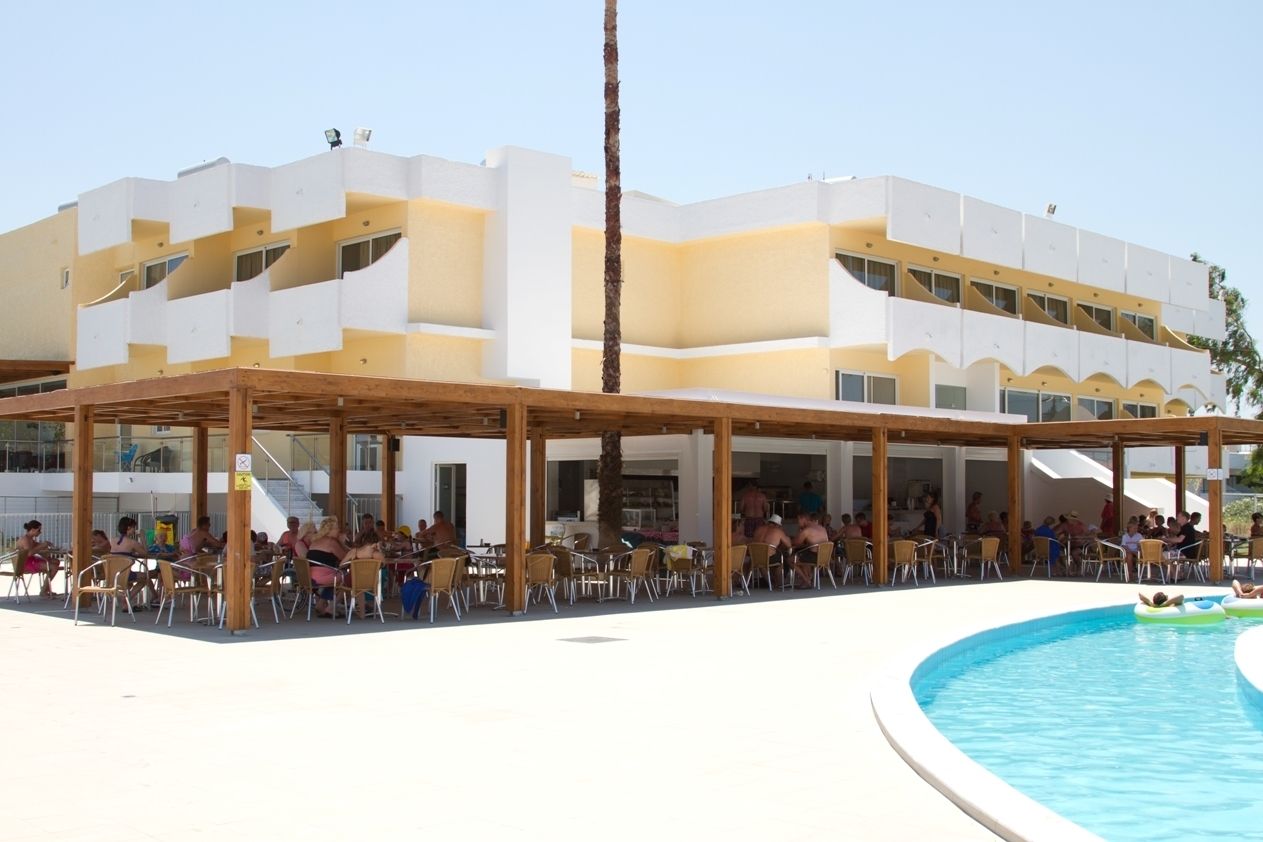 A hotel with a pool area, outdoor seating, and a covered patio.
