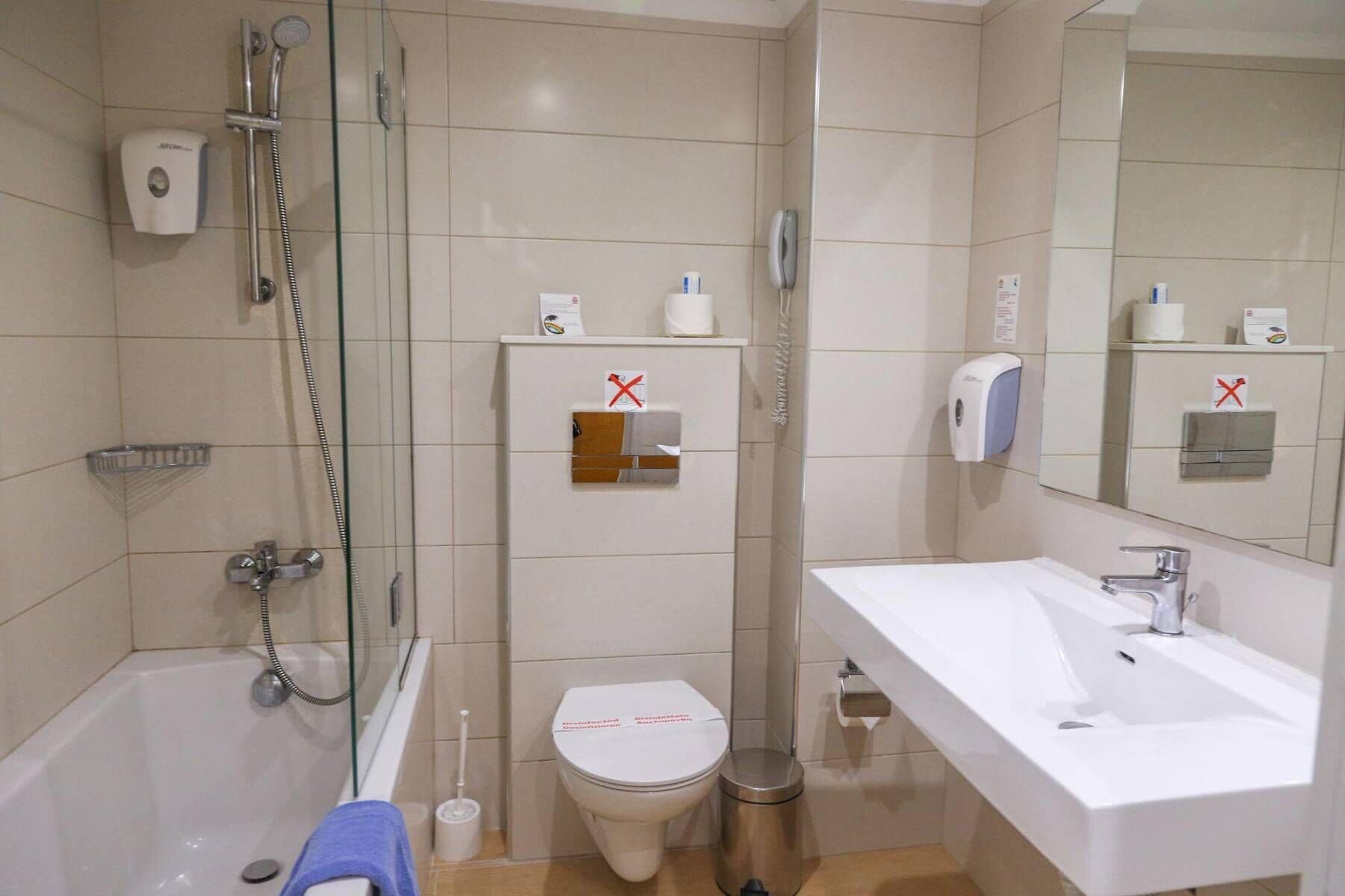 A bathroom with a bathtub, toilet, sink, and glass shower enclosure.