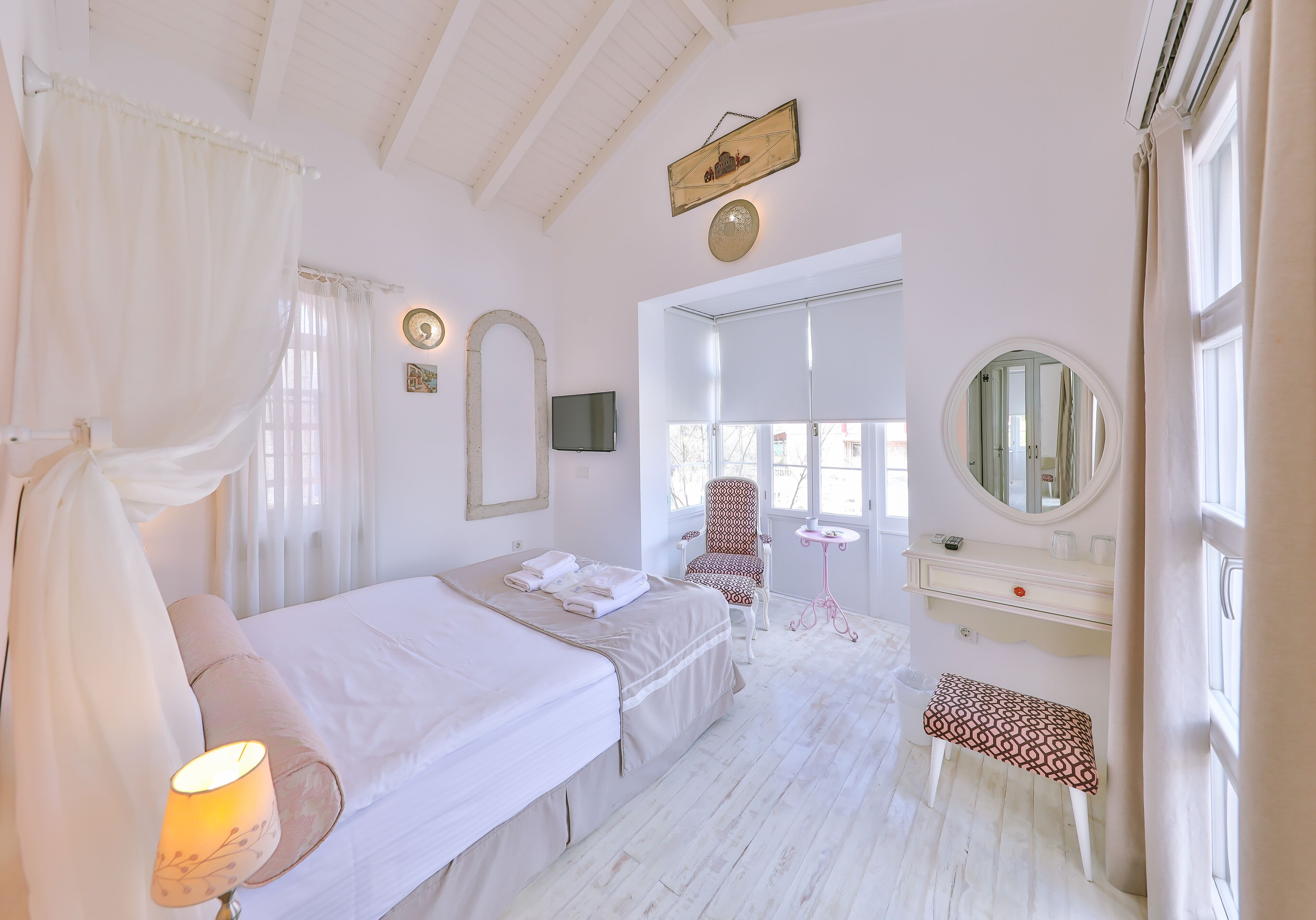 Un dormitorio con cama, mesita de noche, silla, tocador y espejo.