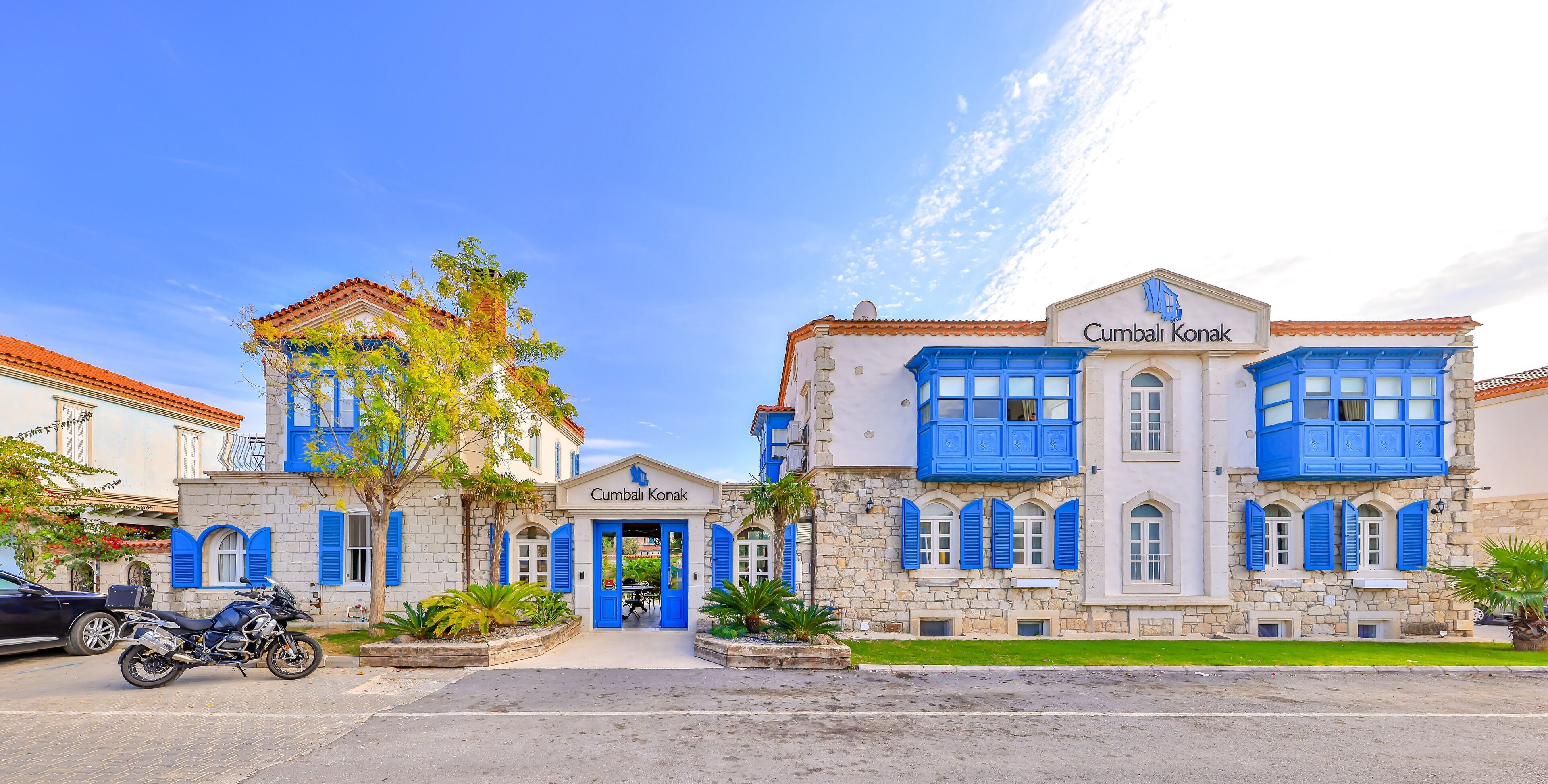 A building with a stone facade and blue shutters, named 'Cumbali Konak'.