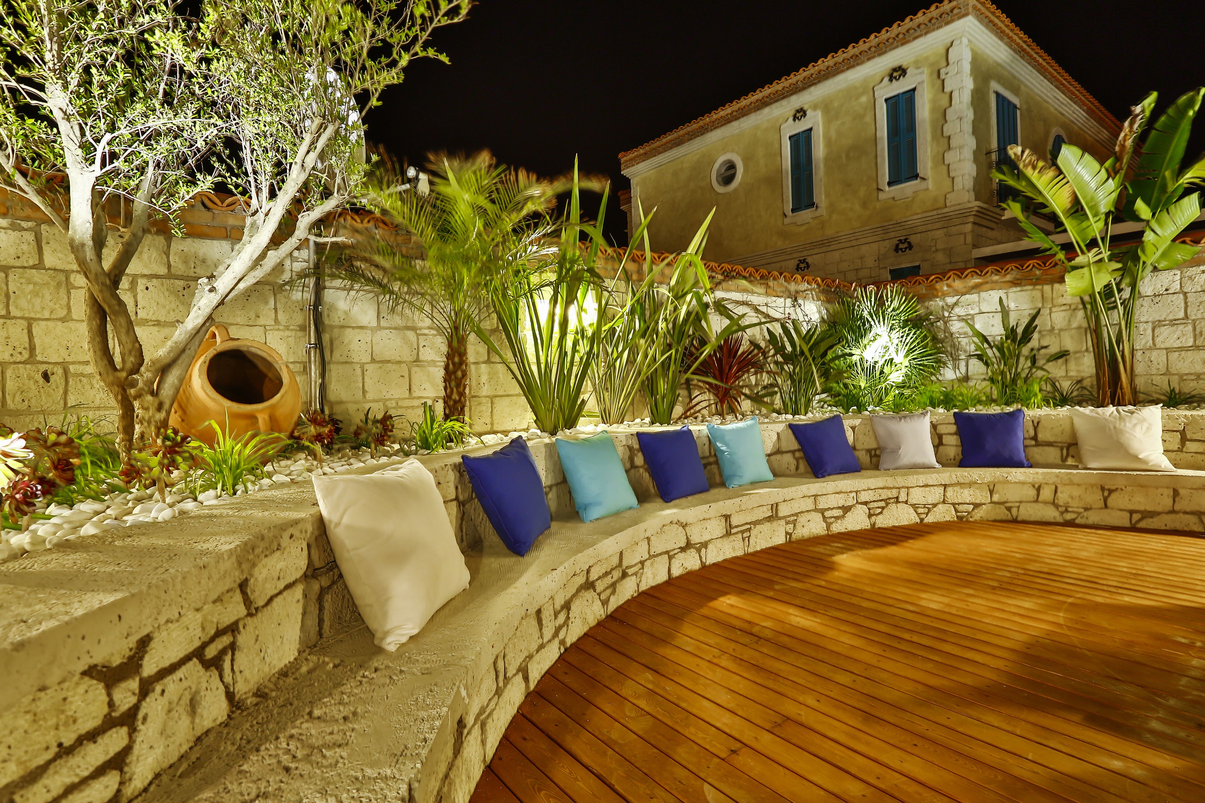 A stone archway leading to a wooden deck with cushions.