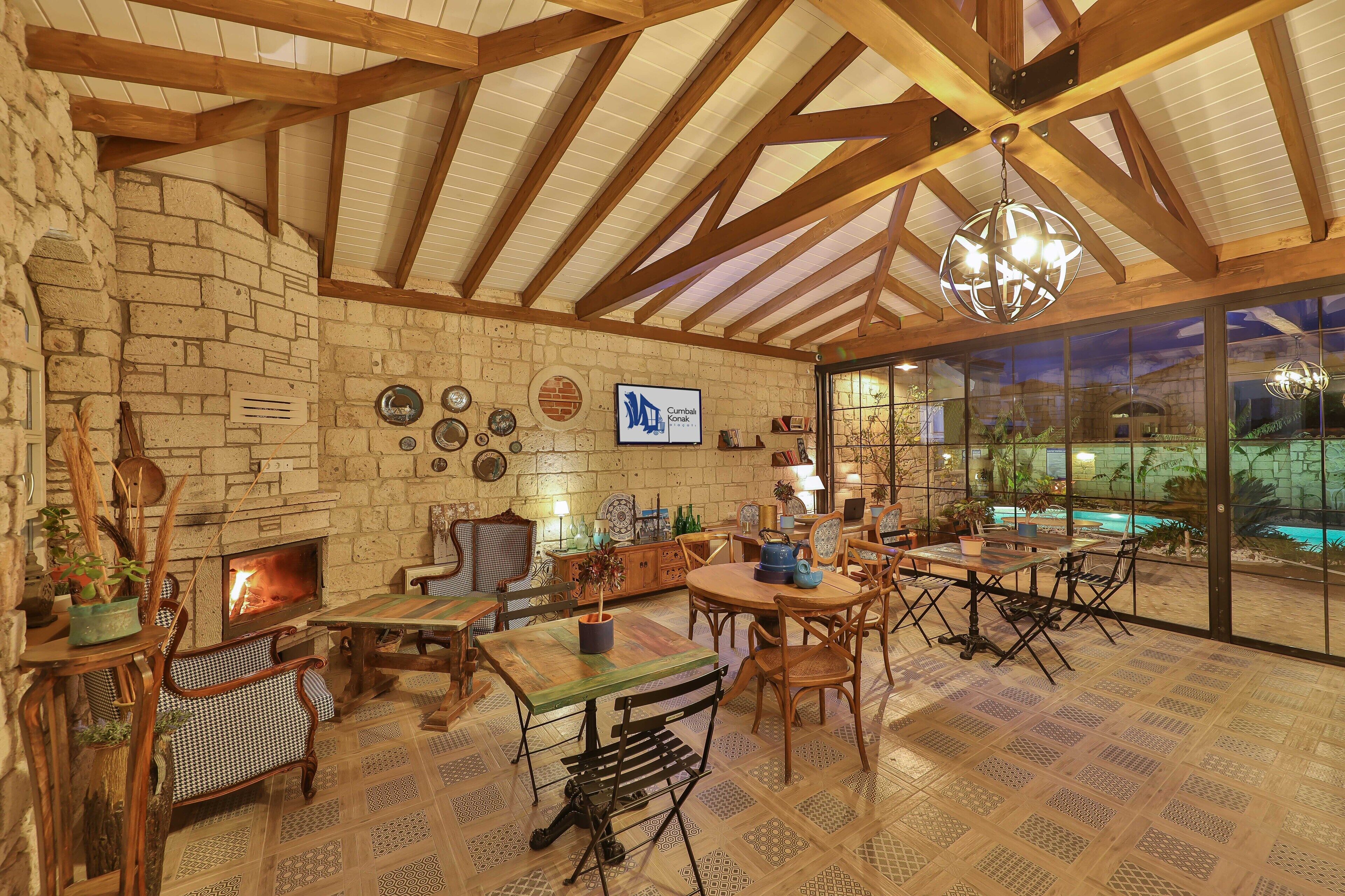 A cozy interior with a fireplace, wooden furniture, and a large window overlooking a pool.