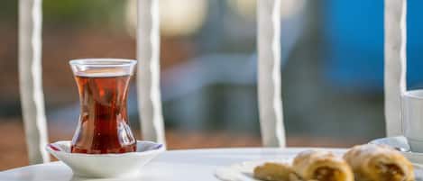 A table with a glass of tea and pastries on a balcony with a railing.