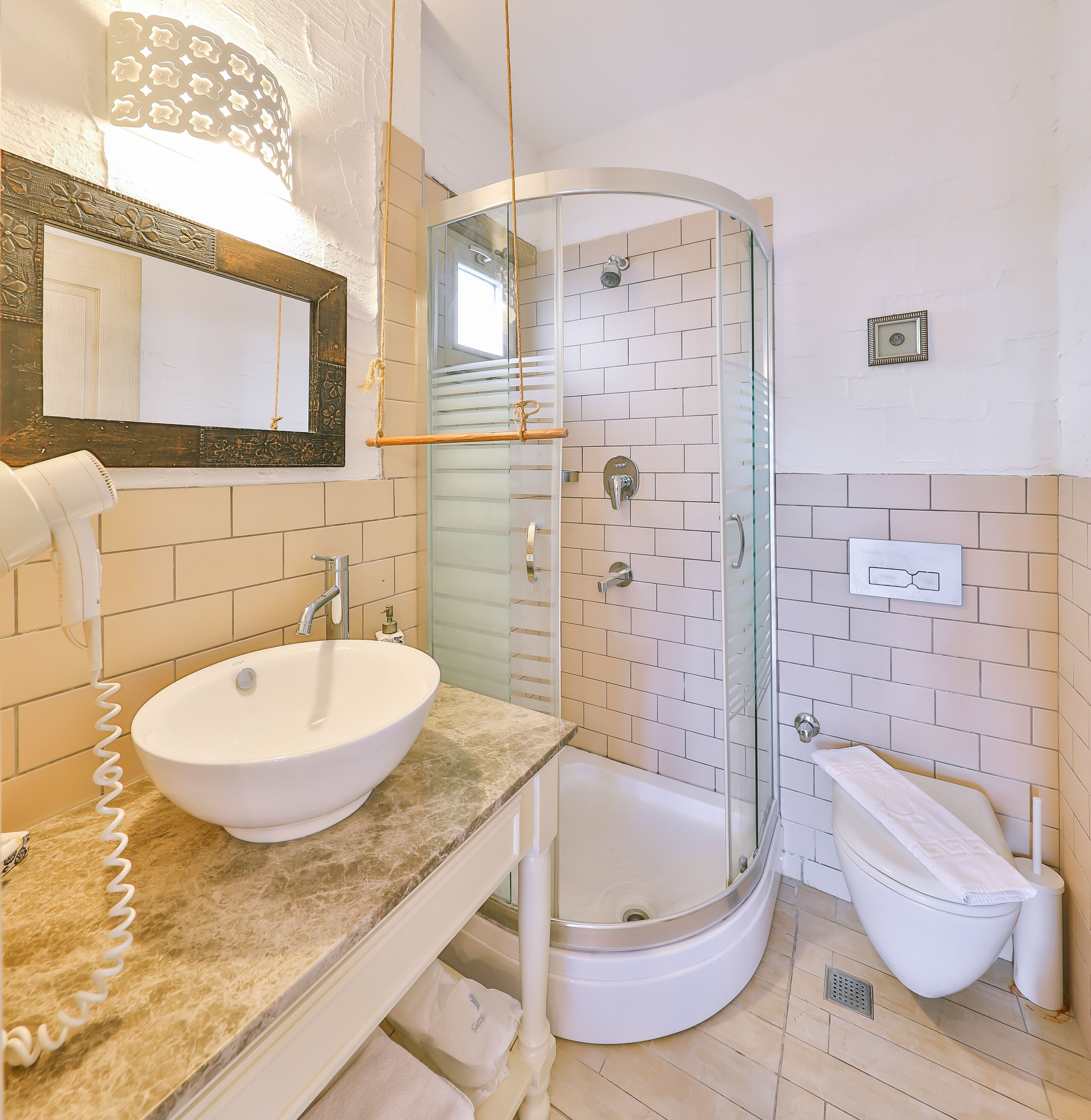 A bathroom with a white sink, a glass-enclosed shower, and a mirror with a decorative frame.