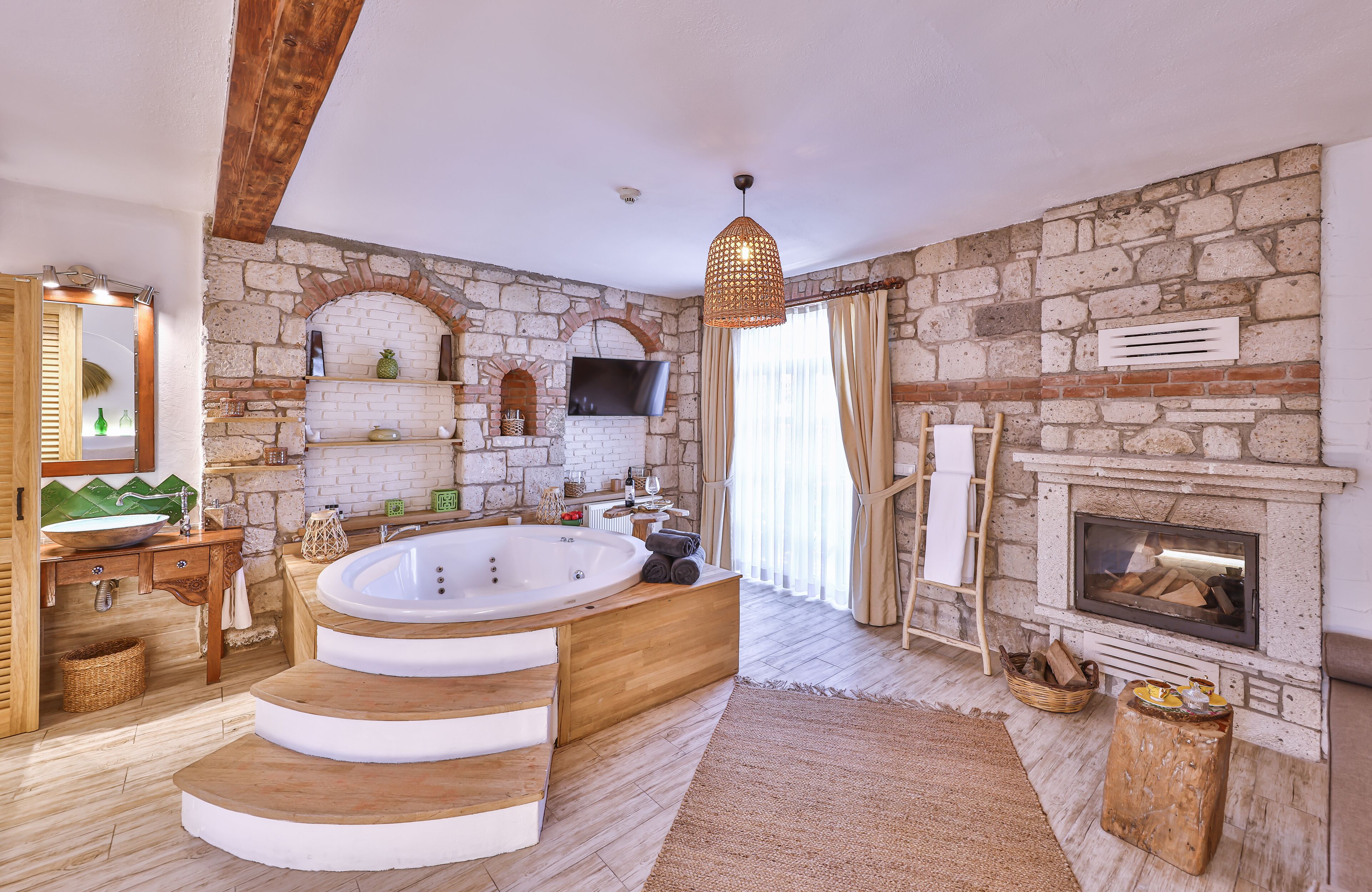 Ein geräumiges Badezimmer mit einer großen Badewanne, einem Holzwaschtisch, Steinwänden und einem Kamin.