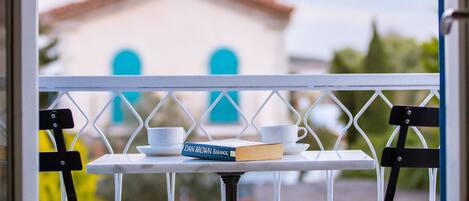 Un balcon avec une table, un livre et une tasse.