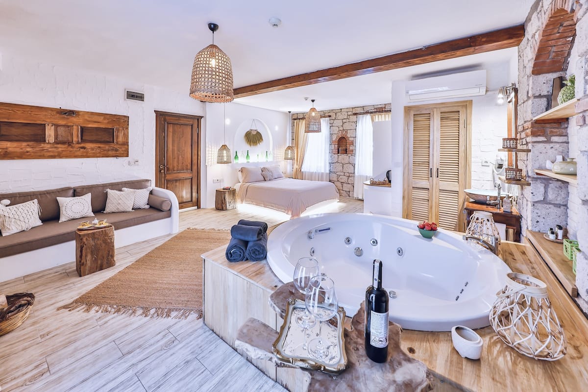 A cozy bedroom with a large bed, a sitting area with a sofa, and a bathtub.