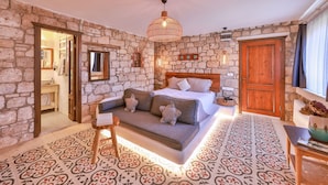 Un dormitorio con paredes de piedra, una cama, un sofá y una mesita.