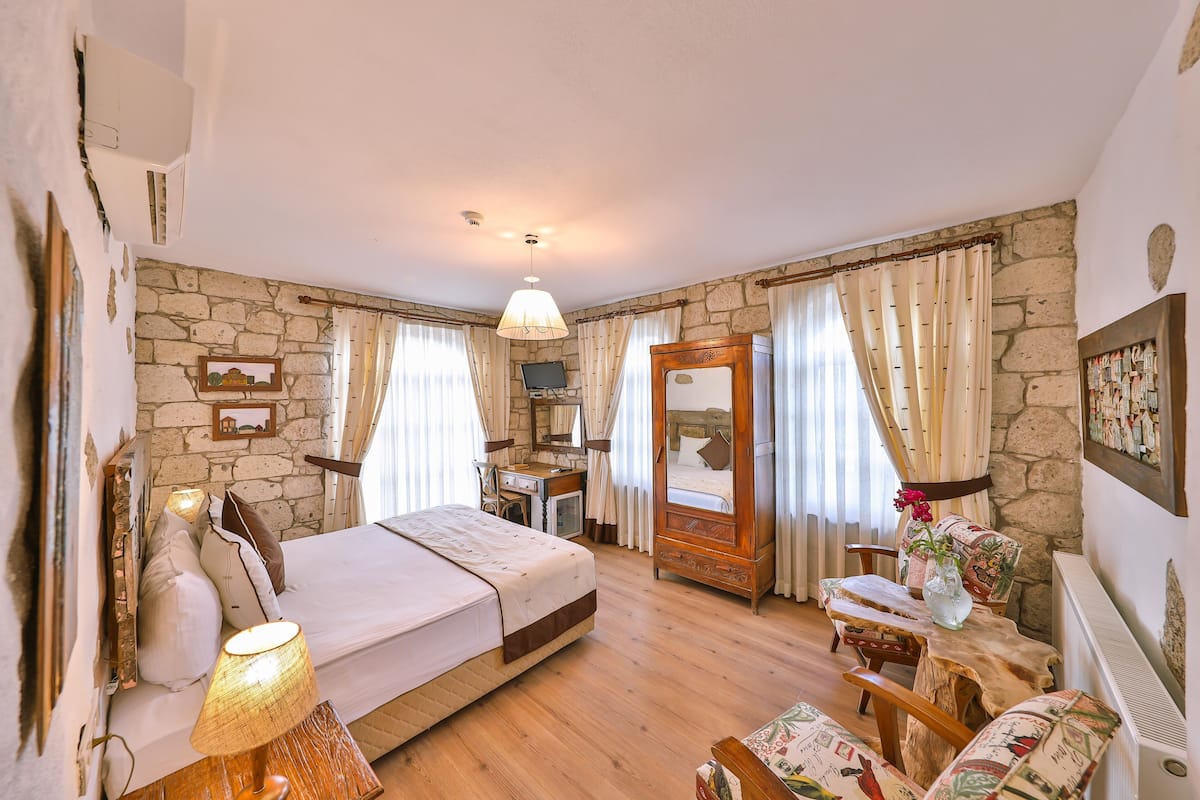 A bedroom with a bed, bedside table, lamp, wooden chair, and a small table with a vase.