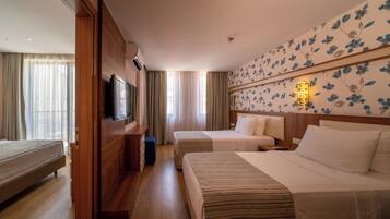 Habitació d'hotel amb llit, televisió, escriptori i armari.
