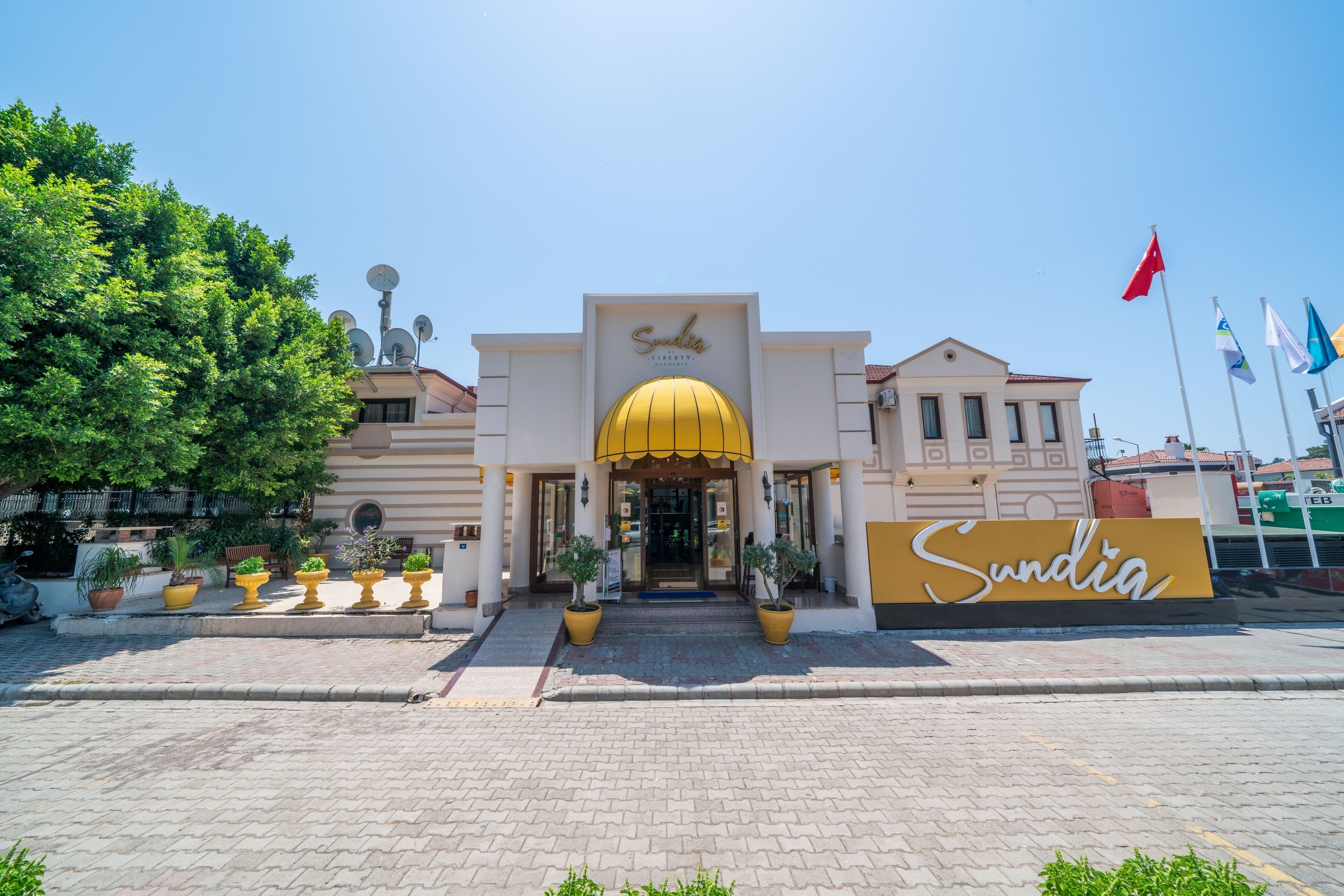A hotel entrance with a yellow dome, a sign reading "Sundia", and multiple flags.