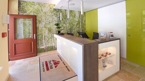 Ein Hotel-Empfangsbereich mit einem Holzbüro, einer grünen Wand und einer Tür.