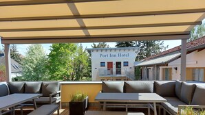 Ein Außenbereich mit Tischen und Bänken, ein Schild für das Port Inn Hotel und eine Aussicht auf Bäume und Gebäude.