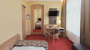 Ein Hotelzimmer mit Bett, Schreibtisch, Stuhl, Fernseher und einem fensterbepflanzten Fenster.