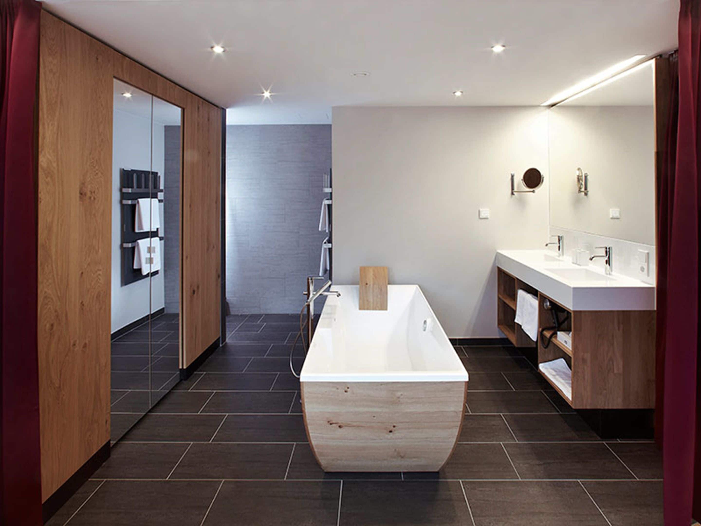 A modern bathroom with a freestanding bathtub, a vanity with two sinks, and a large mirror.