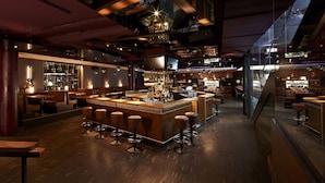 Een bar met een centraal gelegen bar eiland, krukken en een barbalie.