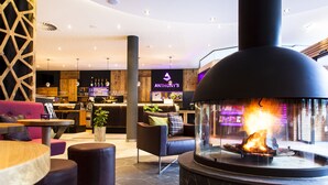 Een modern interieur met een stenen open haard, lederen zitmeubels en een bar met een bord waarop 'Anthony's' staat.