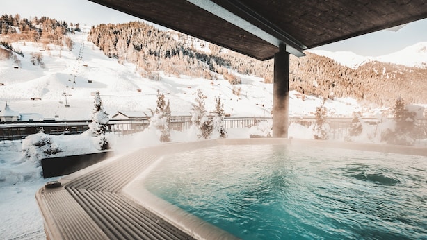Een hottub met uitzicht op een besneeuwd berglandschap.