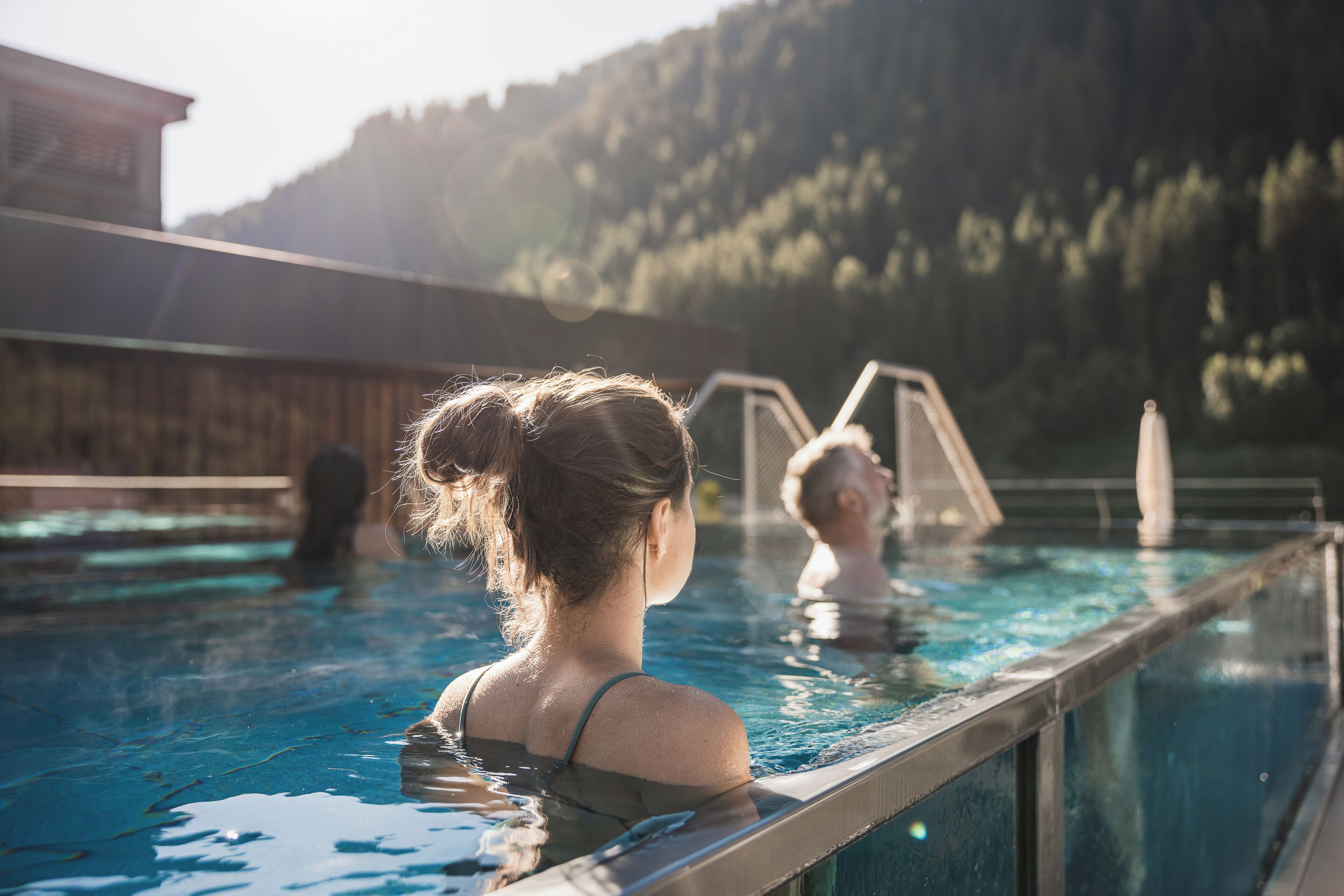Una piscina con cubierta de madera y vista a una ladera boscosa.