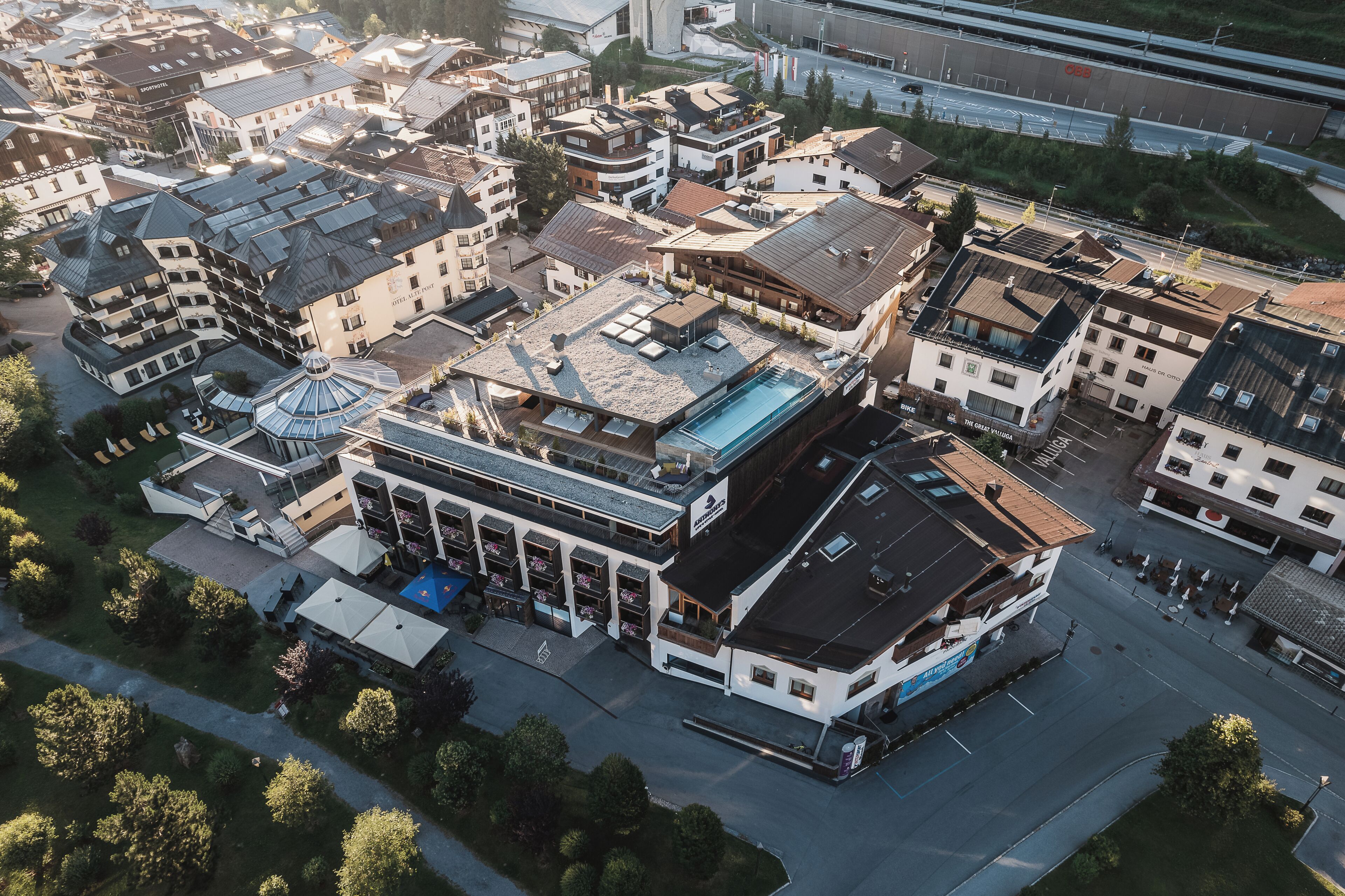 Vista aérea de un complejo hotelero con varias construcciones, una piscina y un estacionamiento.