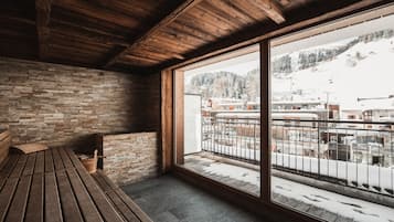 A wooden bench in a room with a large window overlooking a snowy landscape.