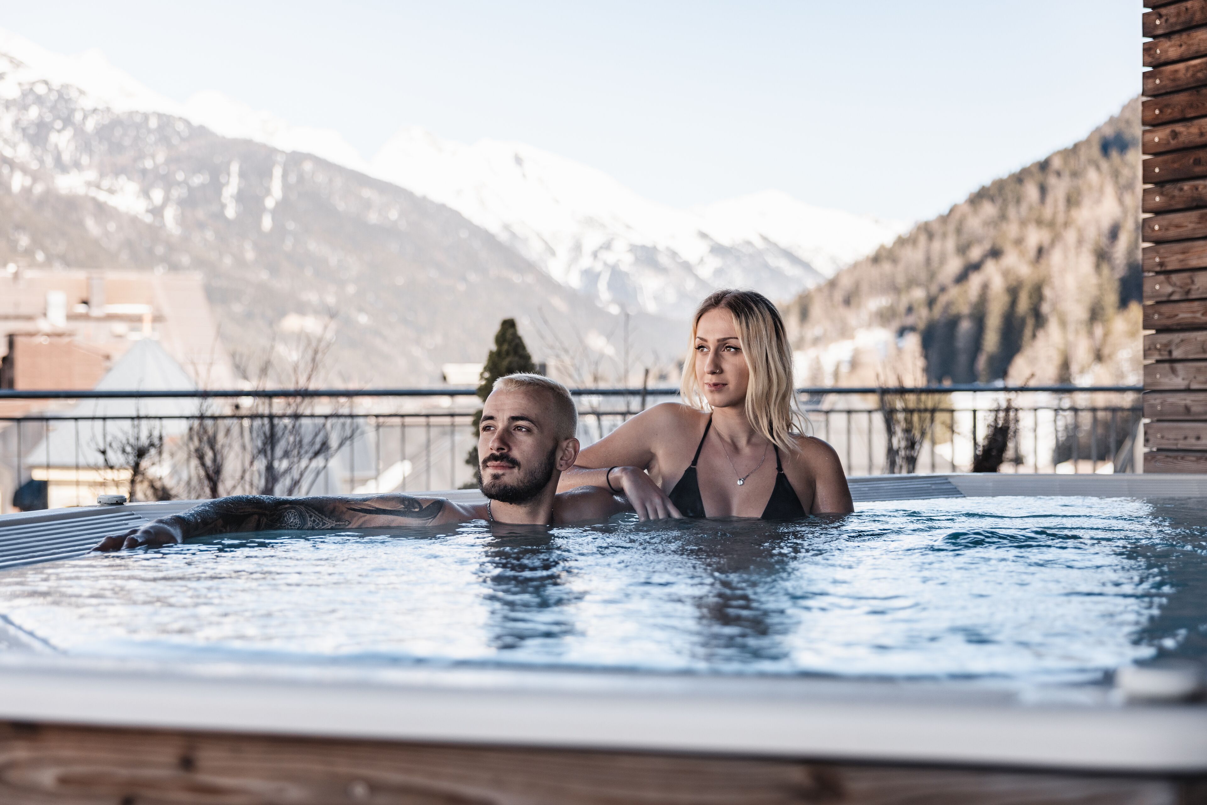 A couple in a hot tub with a mountainous backdrop.