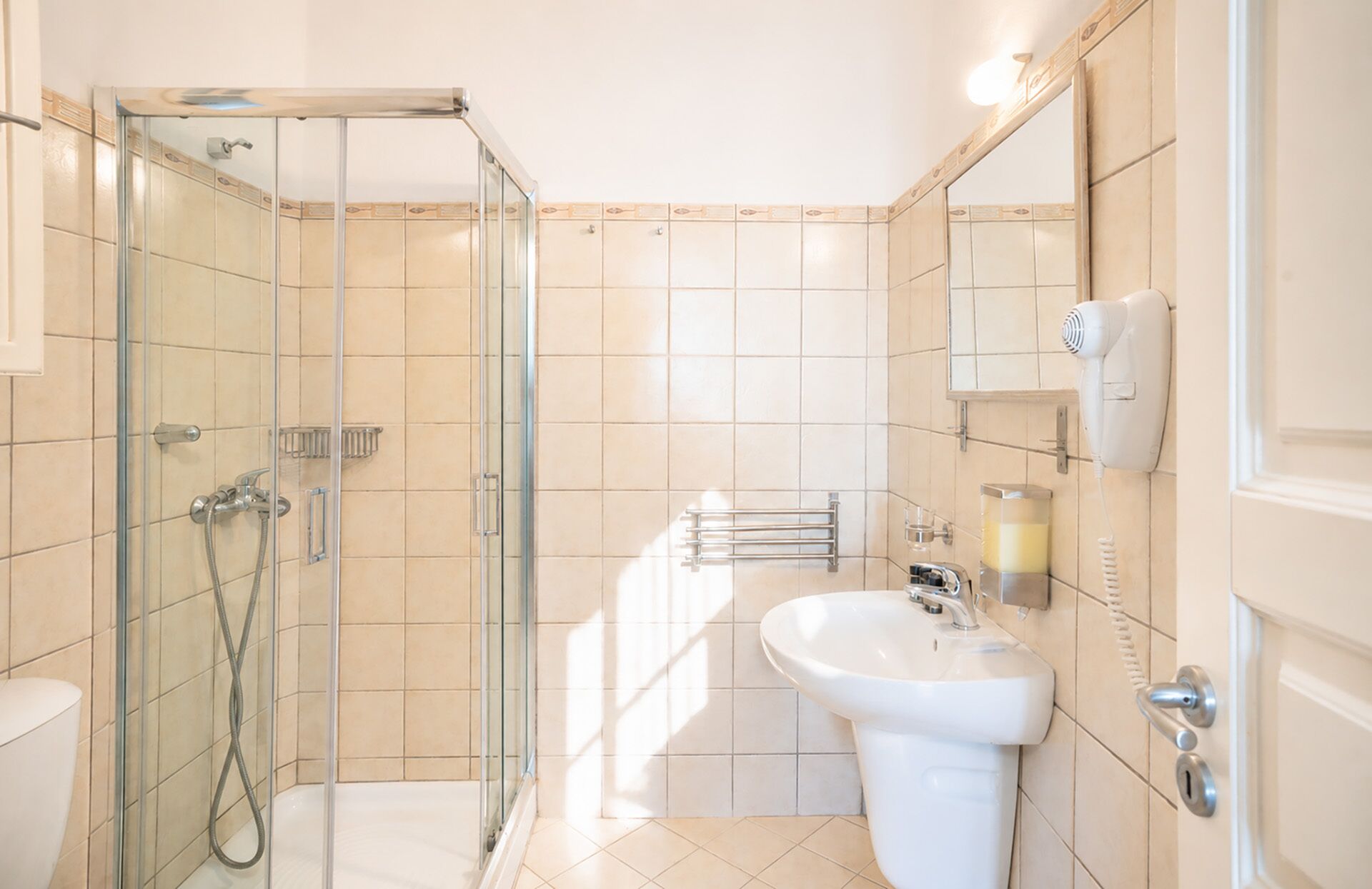 A bathroom with a glass-enclosed shower, a white sink, and a mirror.