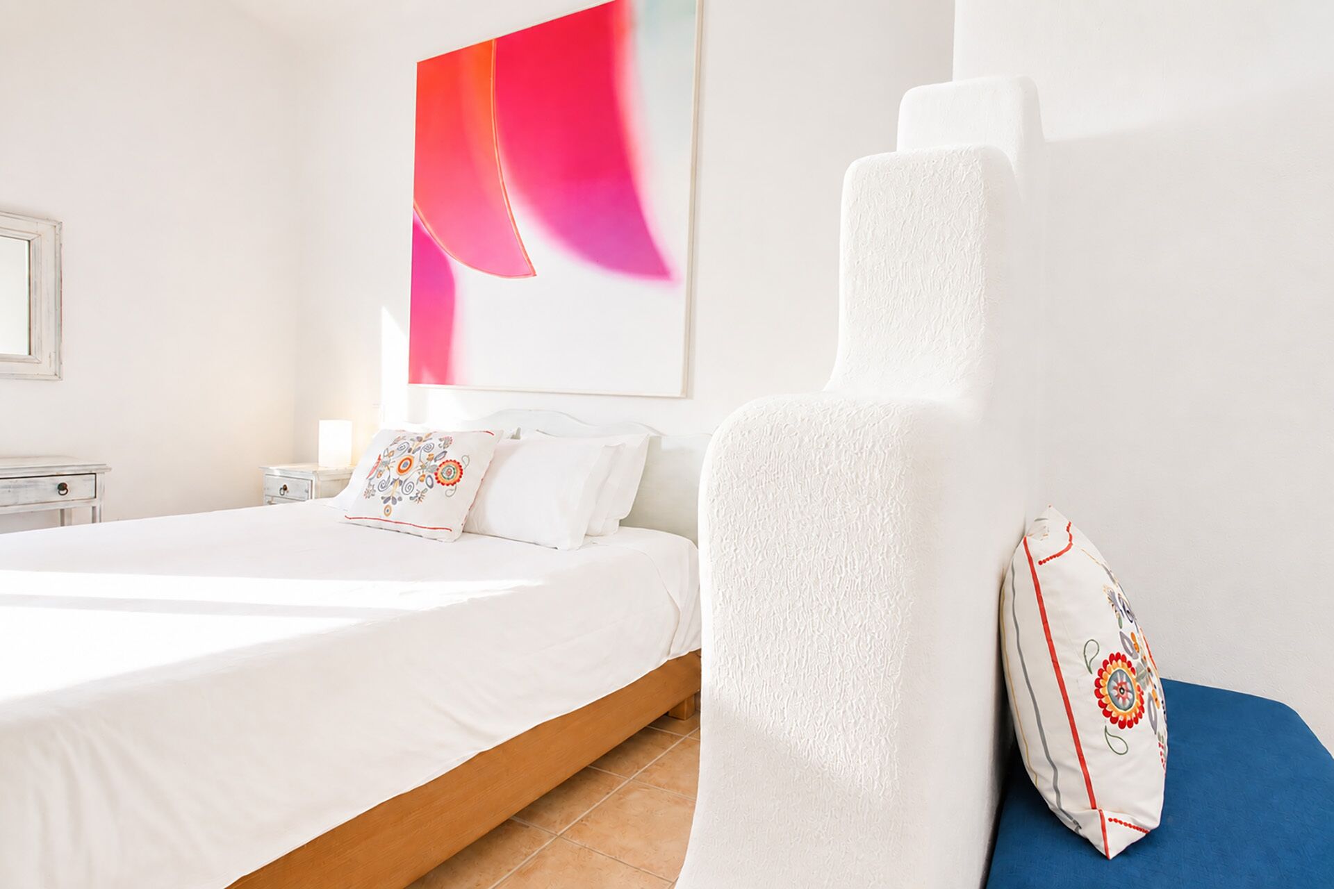 A hotel room with a bed, a nightstand, and a large abstract painting on the wall.