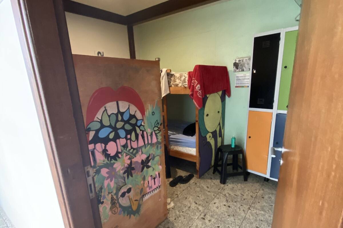 Ein Zimmer mit Etagenbetten, Fliesenboden und einer Tür zu einem weiteren Bereich.