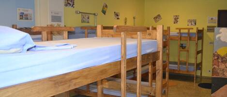 A dormitory room with bunk beds, a desk, and a chair.