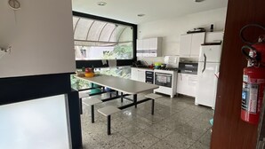 A modern kitchen with white cabinets, a large window, and a tiled floor. - Nomade In Arte e Hostel São Paulo (São Paulo)