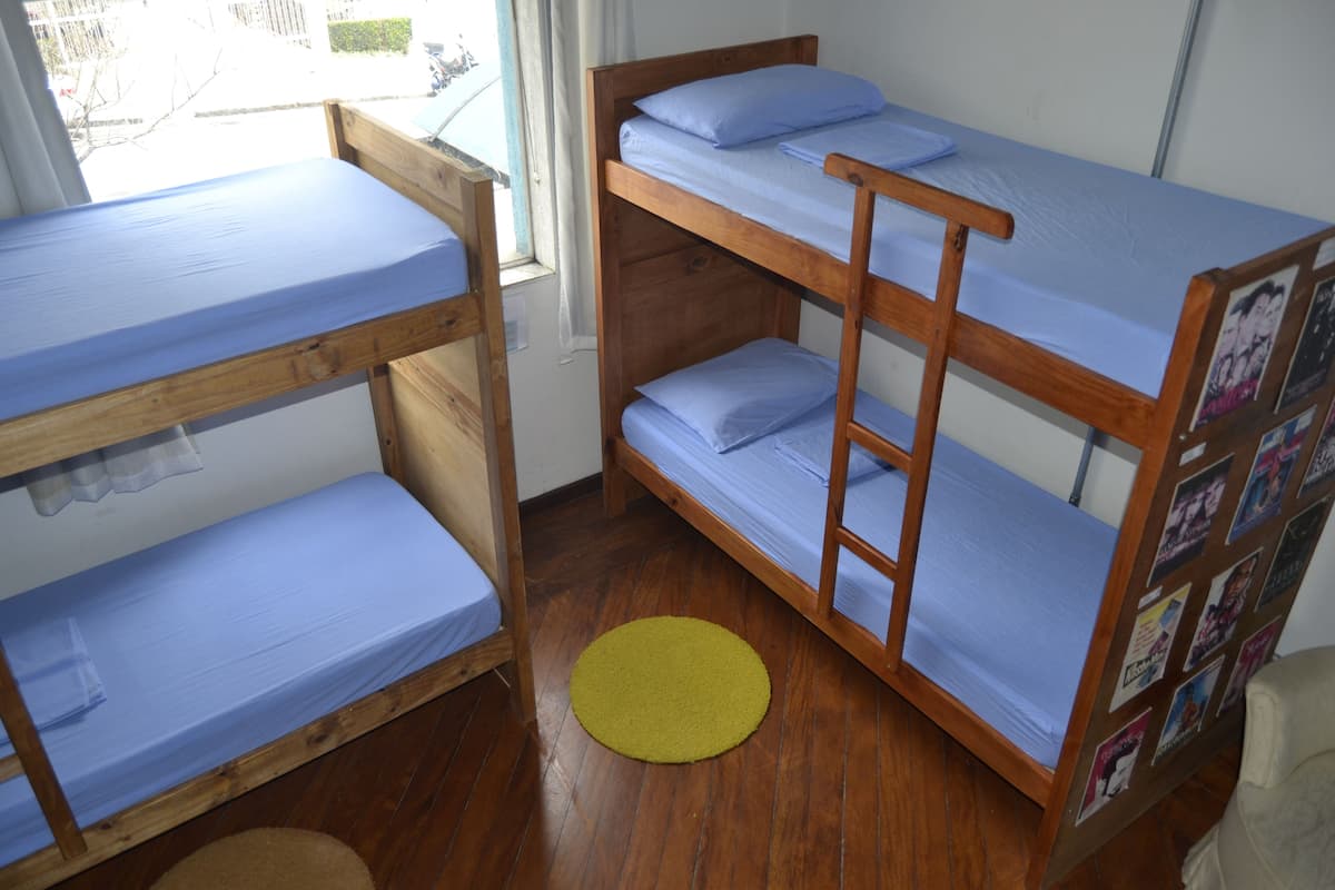 Ein Schlafsaalzimmer mit Etagenbetten, Holzboden und einem gelben Teppich.