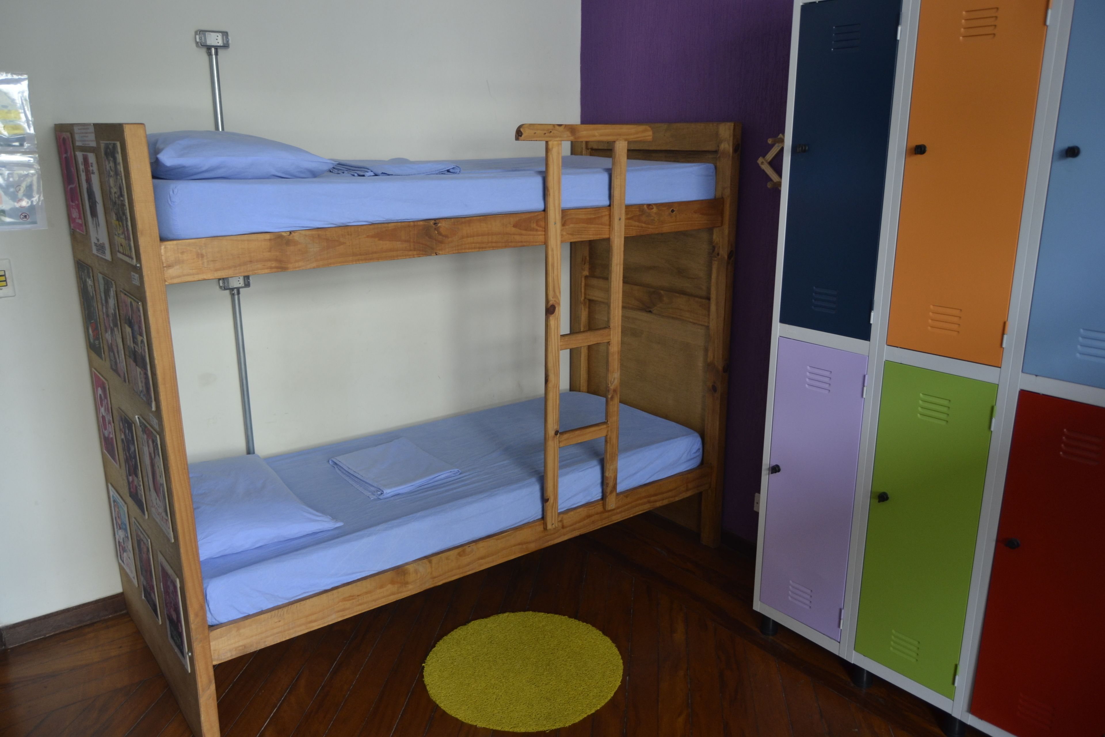 A bunk bed with a ladder, a yellow rug, and colorful lockers.