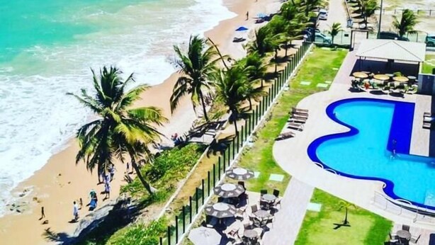 Un resort con piscina, spiaggia e palme.