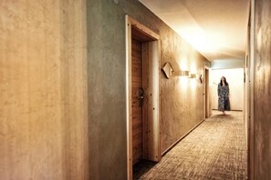 A hallway with wooden doors and a carpeted floor. - Die Seefelderin - Boutiquehotel St. Georg (Seefeld in Tirol)