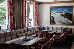 A cozy seating area with a sofa and chairs, a table with a candle, and a painting of a mountain landscape. - Die Seefelderin - Boutiquehotel St. Georg (Seefeld in Tirol)