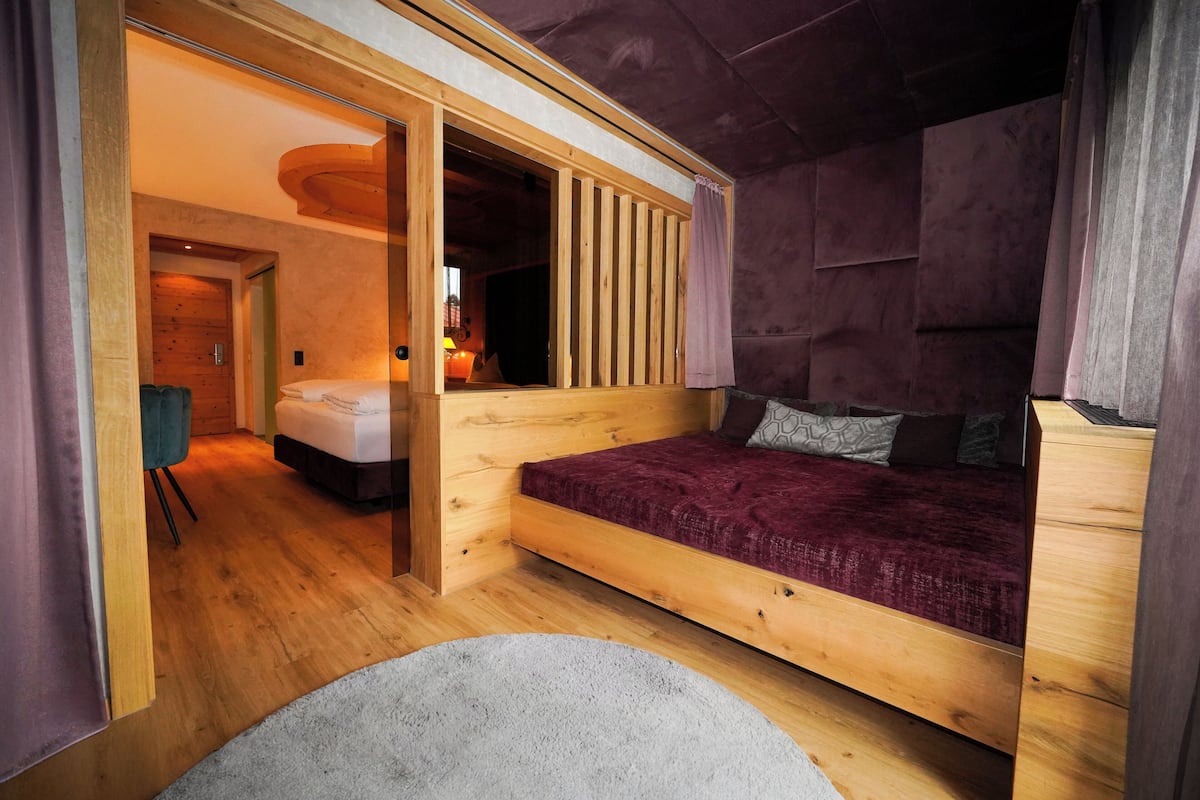 A wooden room with a bed, a desk, and a chair.