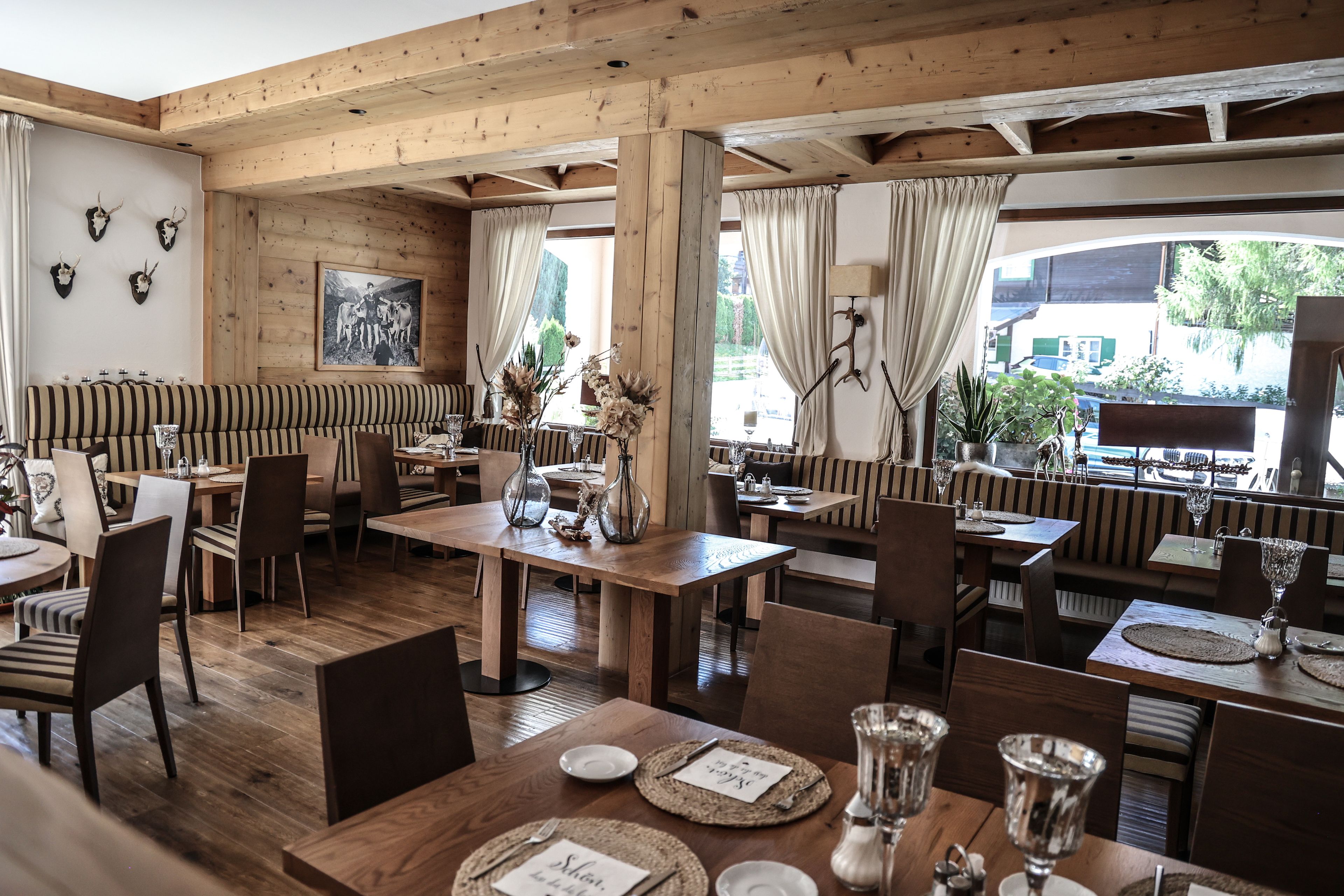 Ein Restaurant mit Holzeinrichtung, gestreifter Sitzbank und Blick ins Freie.