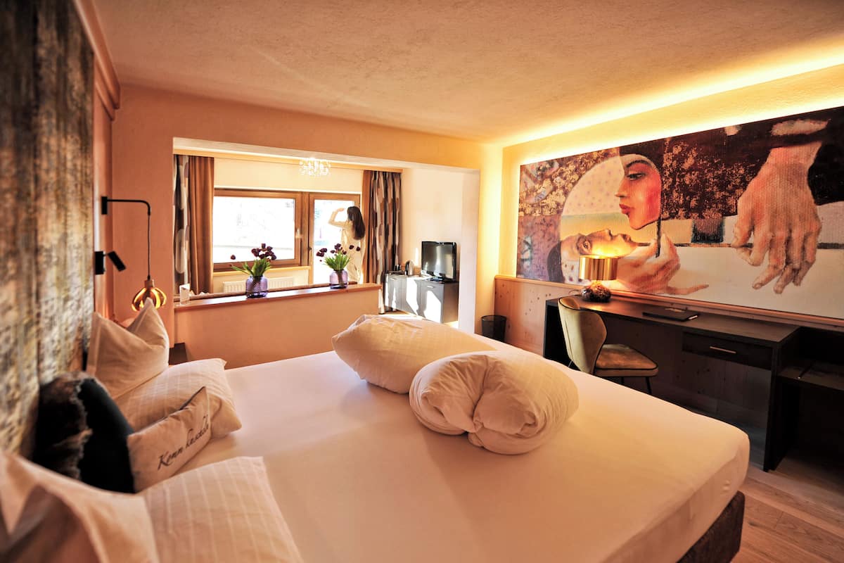 A hotel room with a bed, a desk, a chair, a television, and a window with curtains.