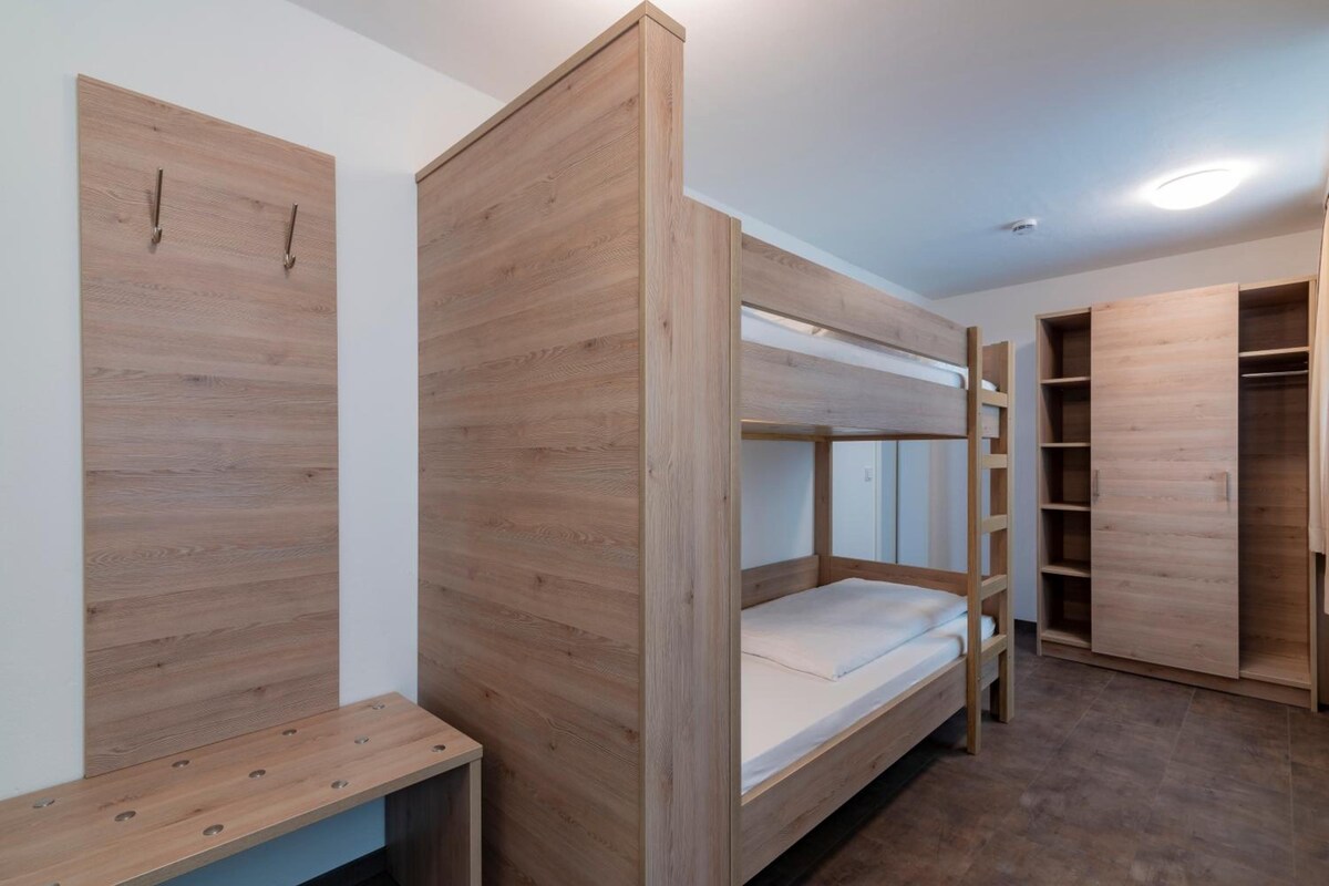 Quarto com beliche, escrivaninha e guarda-roupa.