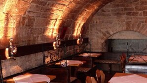 Interior de paredes de piedra con mesas y sillas dispuestas para comer.