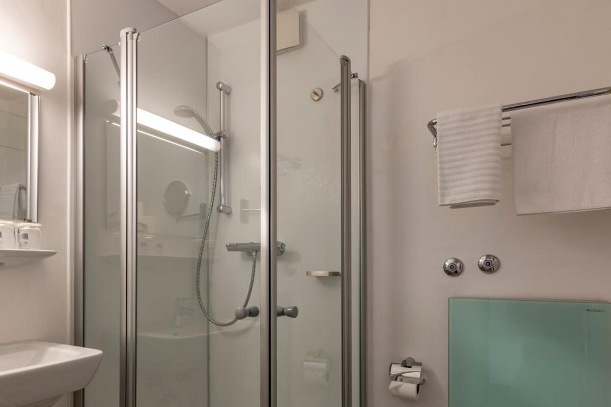 A modern bathroom with a glass-enclosed shower, a white sink, and a toilet.