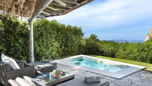 A private pool area with outdoor furniture, a table with a drink and snacks, and a view of the sea. - Li Finistreddi Exclusive Country Retreat (Arzachena)