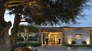 A stone building with a reception area, surrounded by a well-maintained garden and large trees. - Li Finistreddi Exclusive Country Retreat (Arzachena)