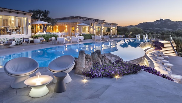 A poolside area with modern seating, a stone feature, and a view of the landscape. - Li Finistreddi Exclusive Country Retreat (Arzachena)