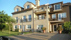 A multi-story residential building with balconies, a paved courtyard, and potted plants. - Casa Mariñeira Lourdes (Cambados)